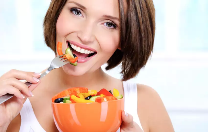 mulher comendo alimentos que clareiam os dentes naturalmente