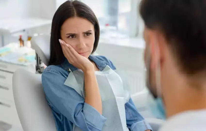 mulher com dores de dente consultando dentista para saber como evitar cáries