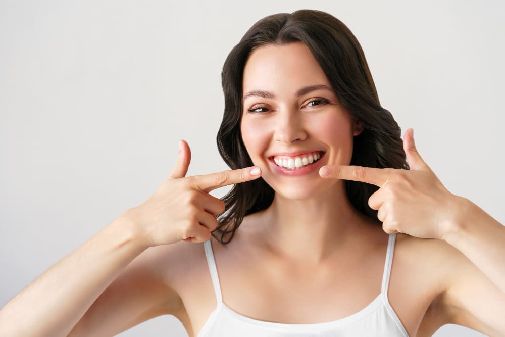 mulher apontando para os dentes claros após usar clareador dental com new white que funciona mesmo