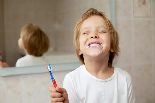 criança escovando dos dentes e aprendendo sobre clareamento dental em crianças